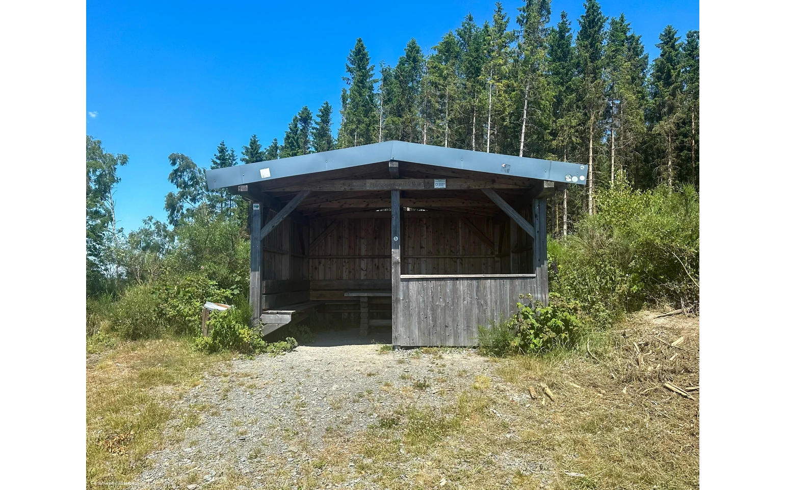 Eine Schutzhütte umgeben von Wald.