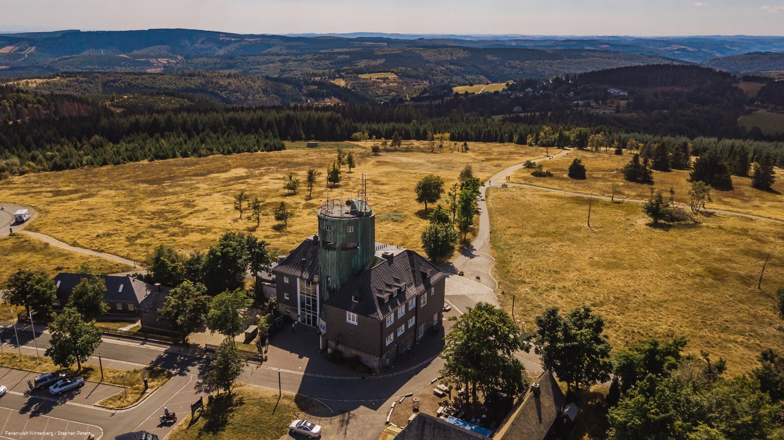 Drohnenaufnahme vom Astenturm mit der Wetterstation umgeben von weiter Heidelandschaft und Wäldern.